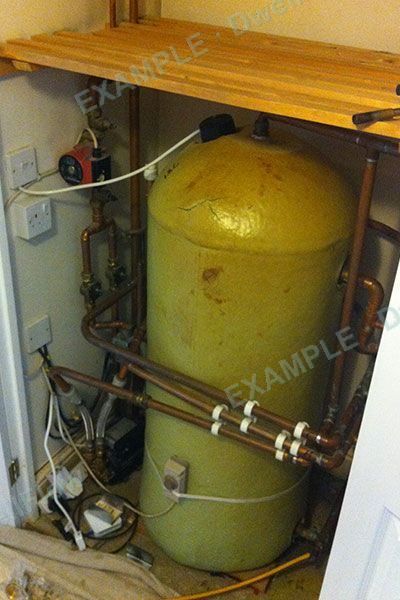 A hot water cylinder in an airing cupboard, with copper pipes and a pump beside it